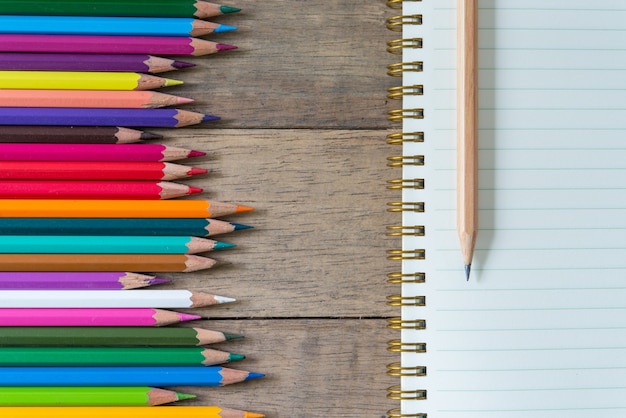 Colored pencils and note book on a wooden