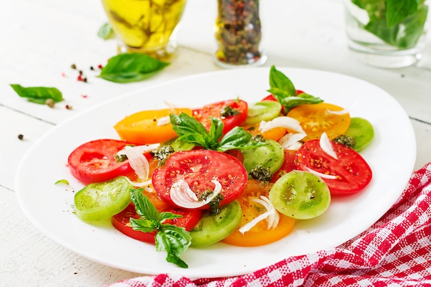 Free photo colored tomato salad with onion and basil pesto.