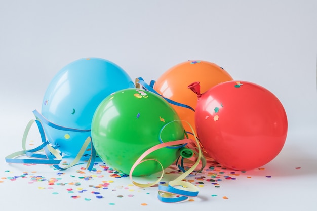 Free photo colorful balloons on the paper confettis on a white surface