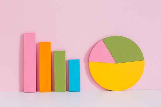 Free photo colorful bar graph and pie chart on desk over pink background