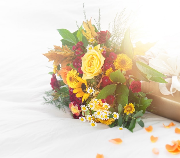 Free photo colorful beautiful spring or summer bouquet of flowers on bed with golden gift box, holiday or surprise concept