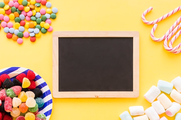 Colorful candies, mint cane and marshmallow on the yellow backdrop