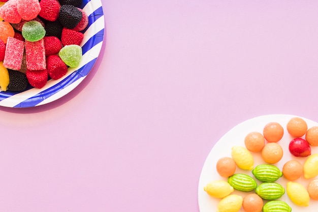 Colorful candies plate on the pink background corner