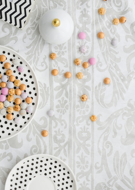 Free photo colorful candies on polkadot plates over the floral tablecloth