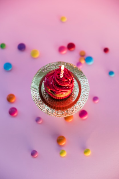 Free photo colorful candies spread over the light cupcake on pink background