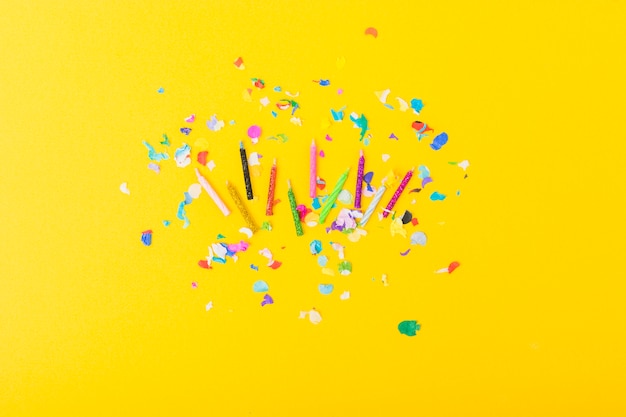 Free photo colorful candles with confetti on yellow background