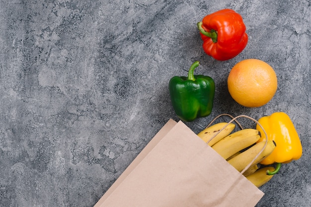 Colorful capsicum; orange and bananas on gray concrete background