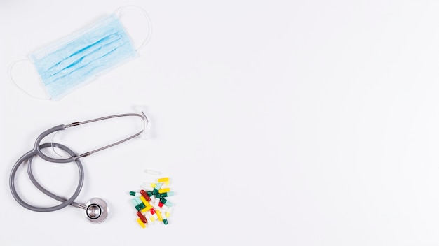 Colorful capsules; stethoscope and mask on white background