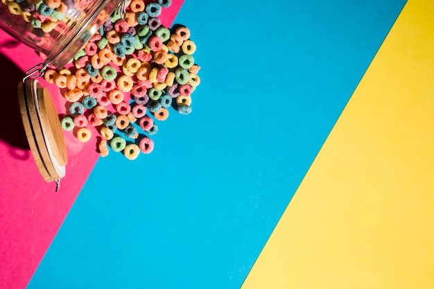 Colorful cereal loop rings spilling from jar on colorful backdrop