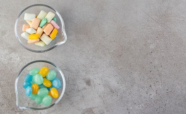 Free photo colorful chewing gums in bowls placed on a stone table .