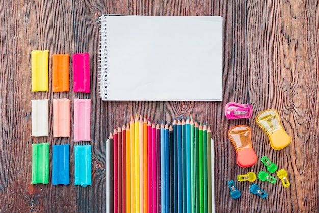 Free photo colorful clay and pencil with white spiral notepad on wooden table