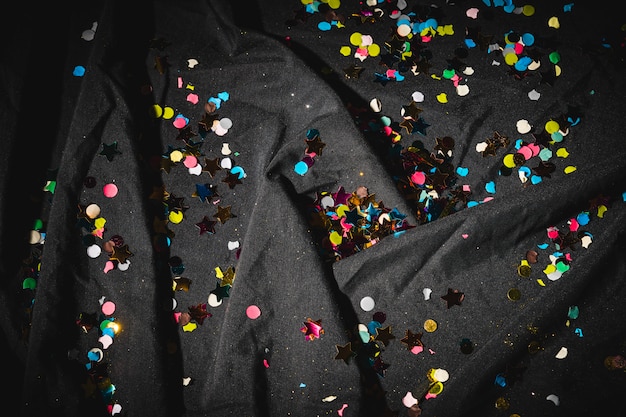 Colorful confetti on dark crumpled cloth