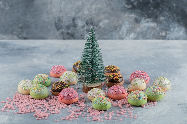 Free Photo colorful cookies decorated with sprinkles around pine tree. 