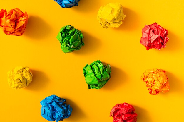 Colorful crumpled paper ball on yellow background