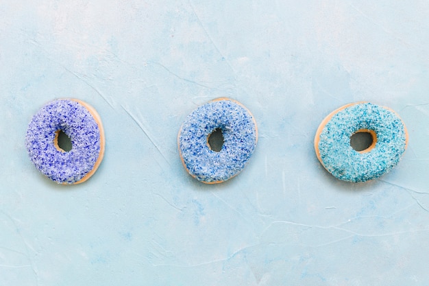 Free Photo colorful donuts in a row on blue backdrop