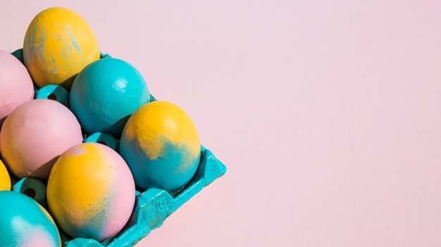 Free photo colorful easter eggs in blue rack on pink table