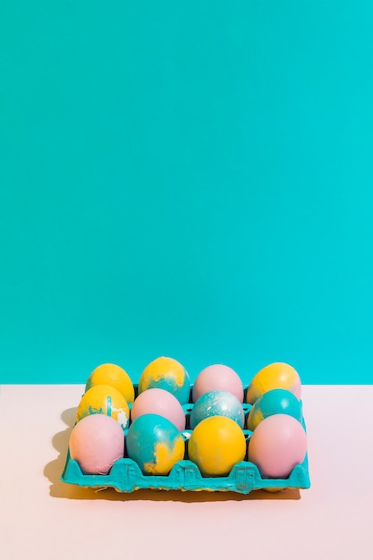 Colorful Easter eggs in bright rack on pink table