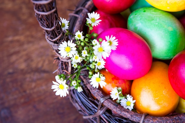 Colorful easter eggs in brown basket with flower