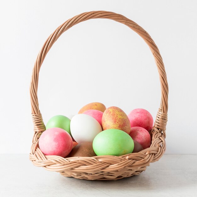 Colorful easter eggs in hay basket front view