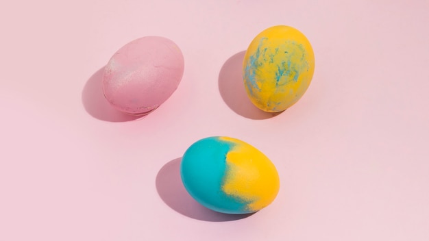 Free photo colorful easter eggs scattered on pink table