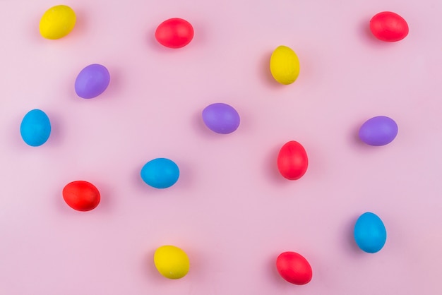 Colorful Easter eggs scattered on pink table