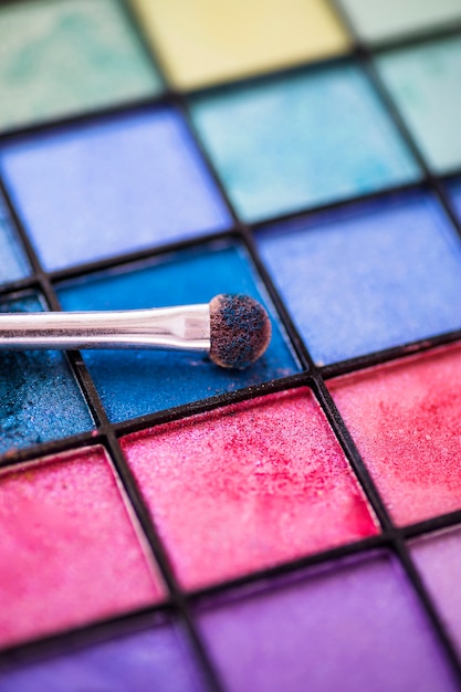 Free photo colorful eye shadow palette background with makeup brush