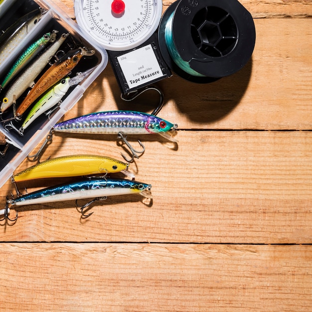 Free photo colorful fishing lure with measuring scale and fishing reel on wooden desk