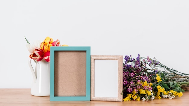 Free photo colorful flowers and photo frames on table