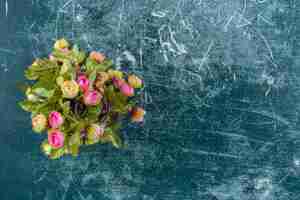 Free photo colorful flowers in a wooden jug , on the blue background.