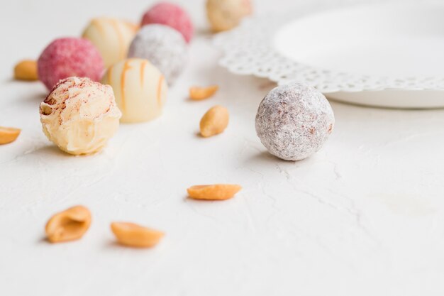 Colorful glazed truffles scattered on white table