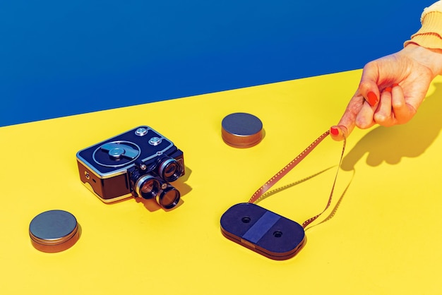 Free photo colorful image of vintage film camera lying on bright yellow tablecloth isolated over blue background