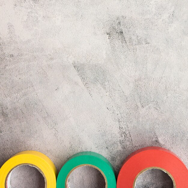 Colorful insulating tape in row on concrete backdrop