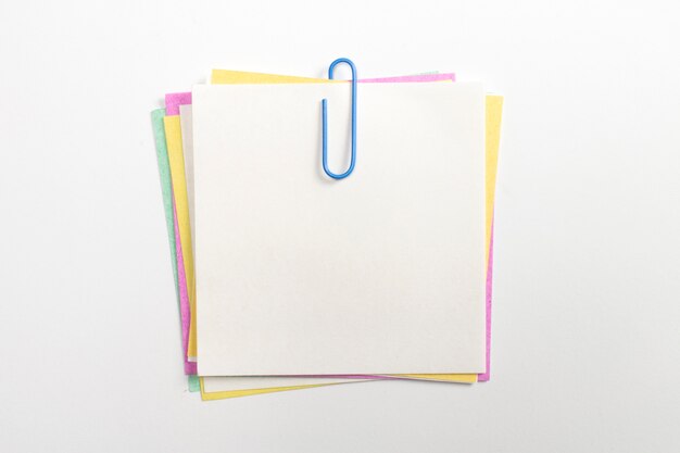 Colorful note paper pin with blue paper clips and isolated on white.