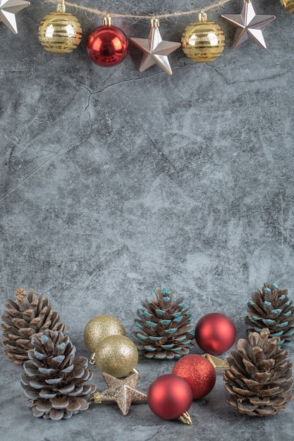 Colorful ornaments hanged from the rustic thread on concrete stone with oak tree cones around