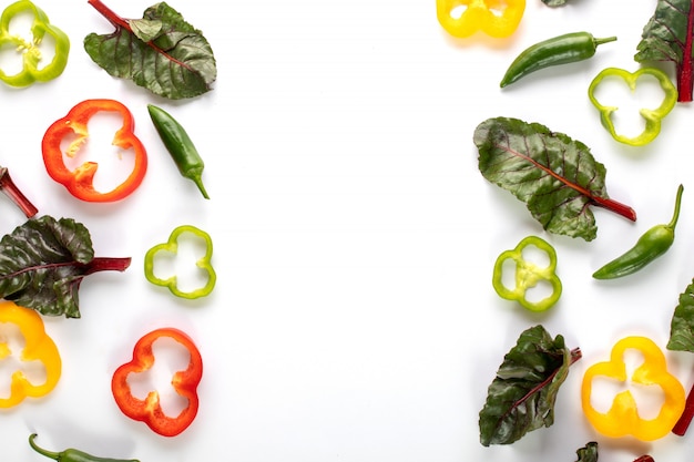 Colorful peppers fresh ripe and sliced bell peppers along with spicy green pepper and leafs on dark background