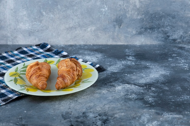 Free photo a colorful plate of fresh croissants placed on a marble table.