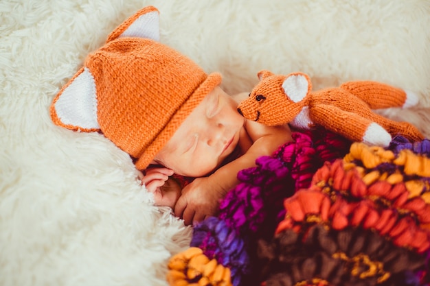 Colorful scarf envelopes little baby in fox hat 