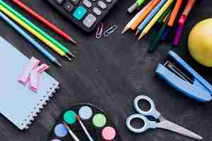 Free photo colorful school stationery scattered on chalkboard