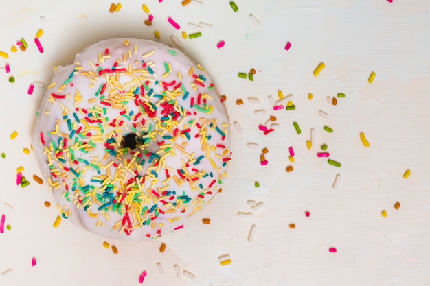 Free photo colorful sprinkles over the white donut against white backdrop