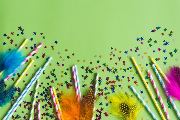 Free Photo colorful sticks with confetti underneath on a green table