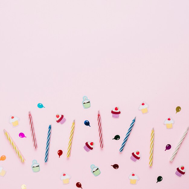 Colorful striped candles with birthday stickers on pink background