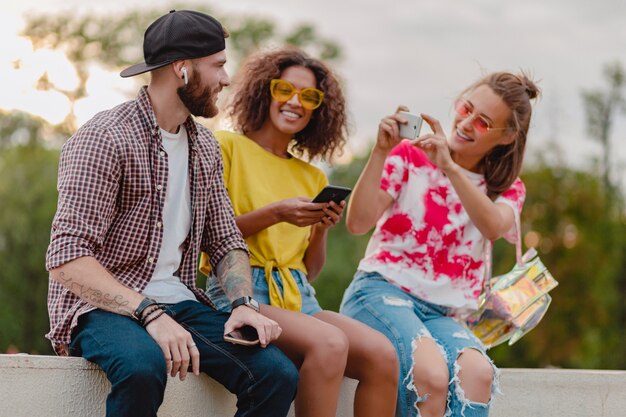 Colorful stylish happy young company of friends sitting park