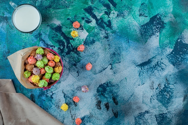 Colorful sugar cereal in a bucket on the blue surface