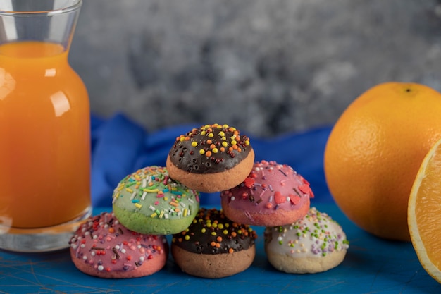 Colorful sweet doughnuts with a glass jar of juice . 