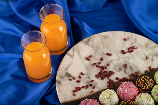 Free photo colorful sweet small doughnuts with bottles of orange juice .