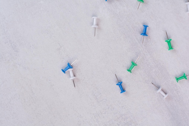 Free photo colorful thumbtacks scattered on white surface.