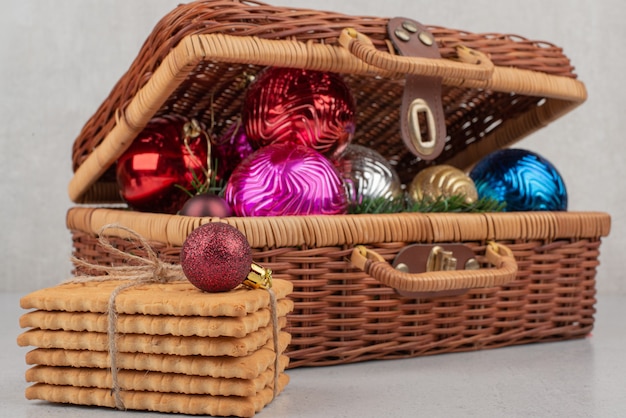 Colourful Christmas balls in basket with cookies in rope .