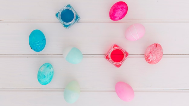 Colourful Easter eggs near cans of dye liquid on desk