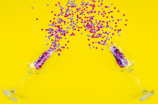 Colourful sequins and glasses on yellow background