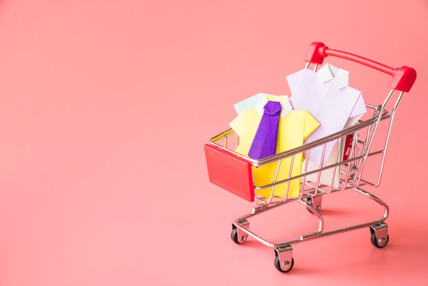 Colourful toy paper shirts in shopping trolley